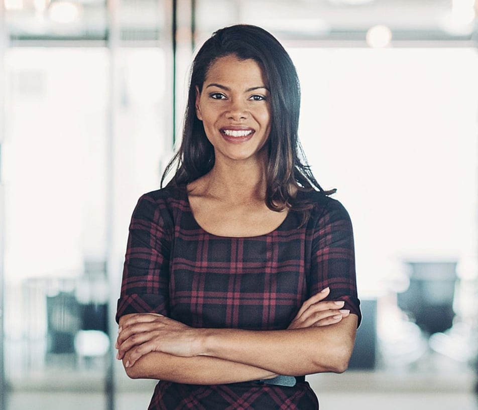 Laura Couvrette smiling in a plaid top standing with arms folded 